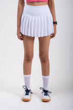 Person wearing a white pleated tennis skirt on a plain background