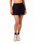Person wearing a black pleated skirt on a white background