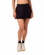 Person wearing a black pleated skirt on a white background