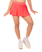 Woman wearing a white sleeveless top and pink pleated skirt on a white background